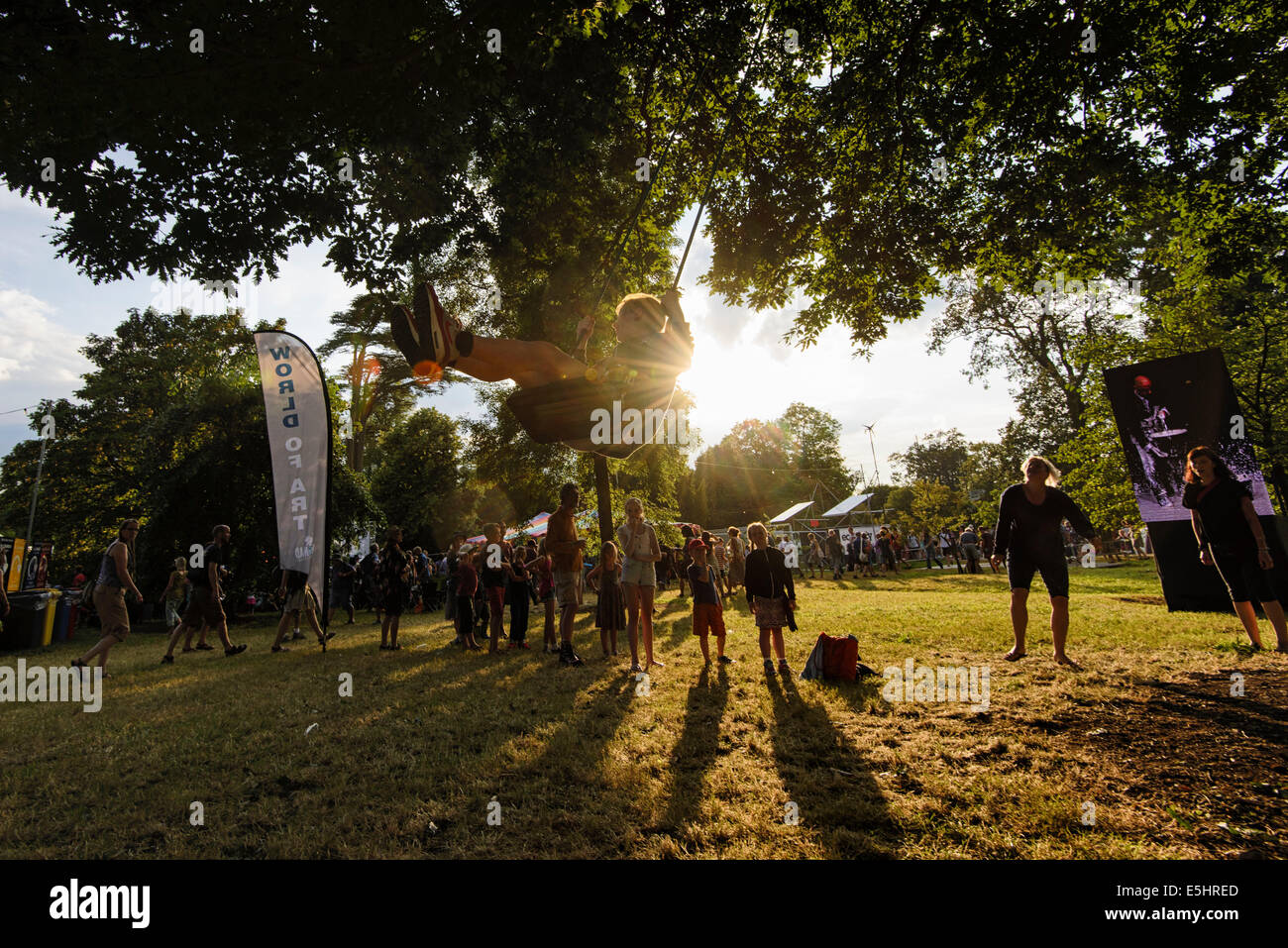 Malmesbury, UK, 25/07/2014 : Atmosphère au monde - WOMAD de la musique, des arts et de la danse. Les enfants jouent n a s'agiter dans les arbres éclairés par un faible soleil du soir. Photo par Julie Edwards Banque D'Images
