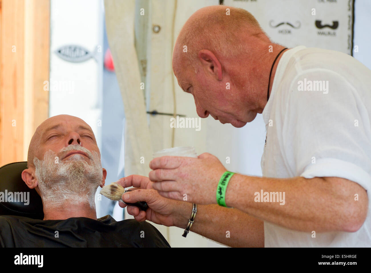 Malmesbury, UK, 26/07/2014 : Atmosphère au monde - WOMAD de la musique, des arts et de la danse. Un homme prend un rasage humide. Photo par Julie Edwards Banque D'Images