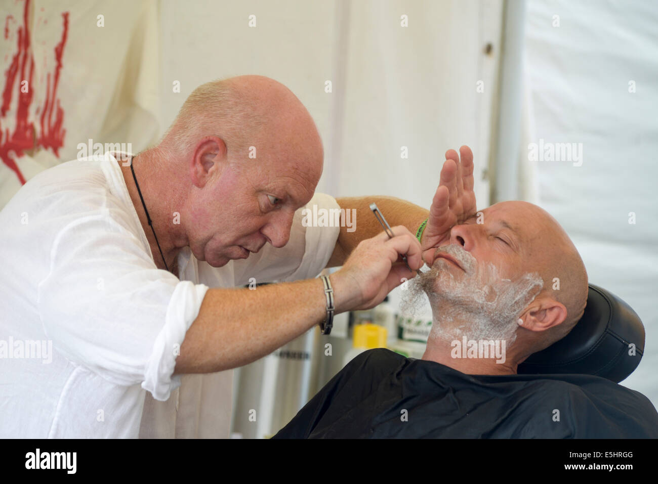Malmesbury, UK, 26/07/2014 : Atmosphère au monde - WOMAD de la musique, des arts et de la danse. Un homme prend un rasage humide. Photo par Julie Edwards Banque D'Images