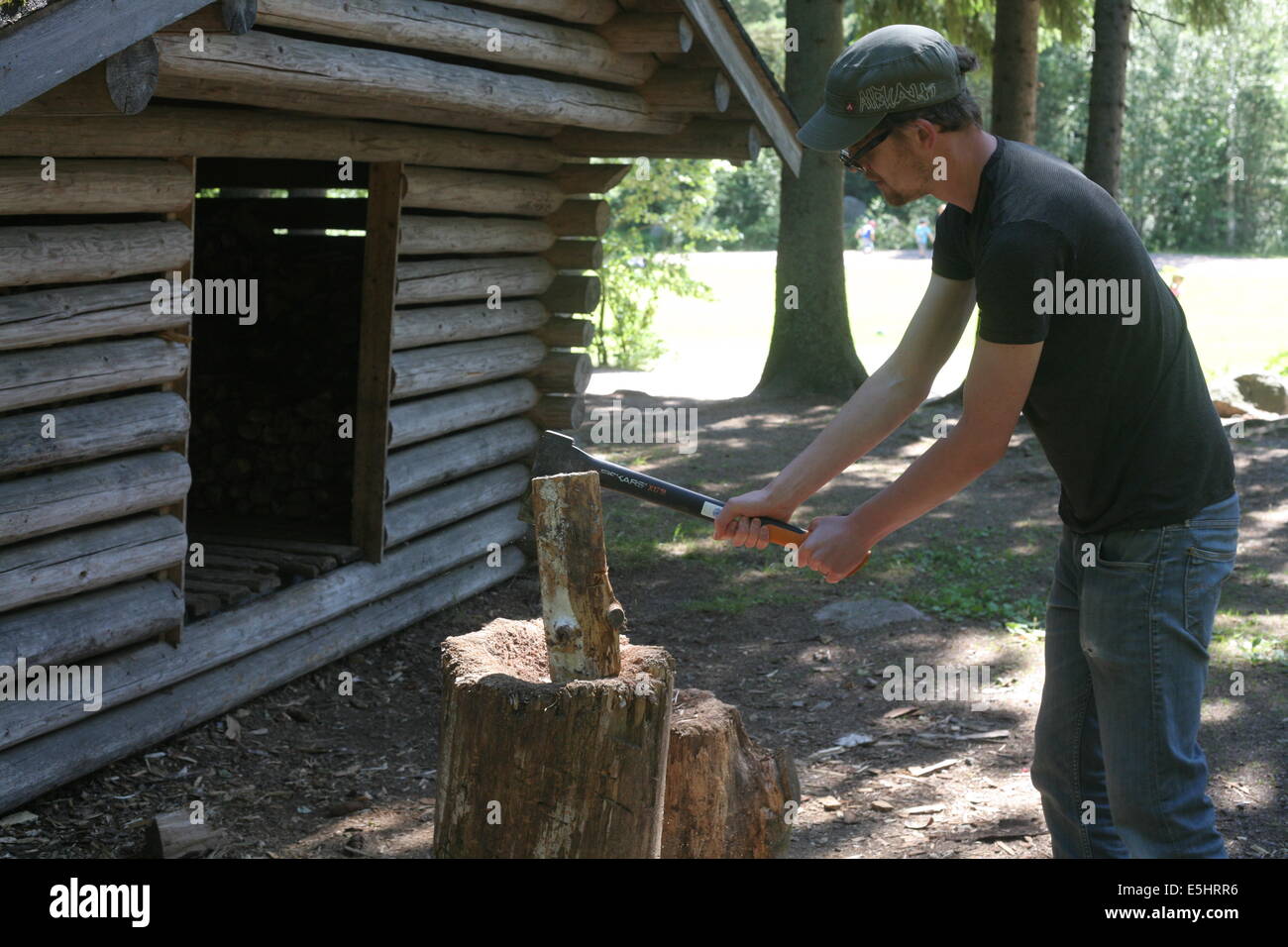 Homme couper du bois à l'extérieur de log cabin, Finlande Banque D'Images