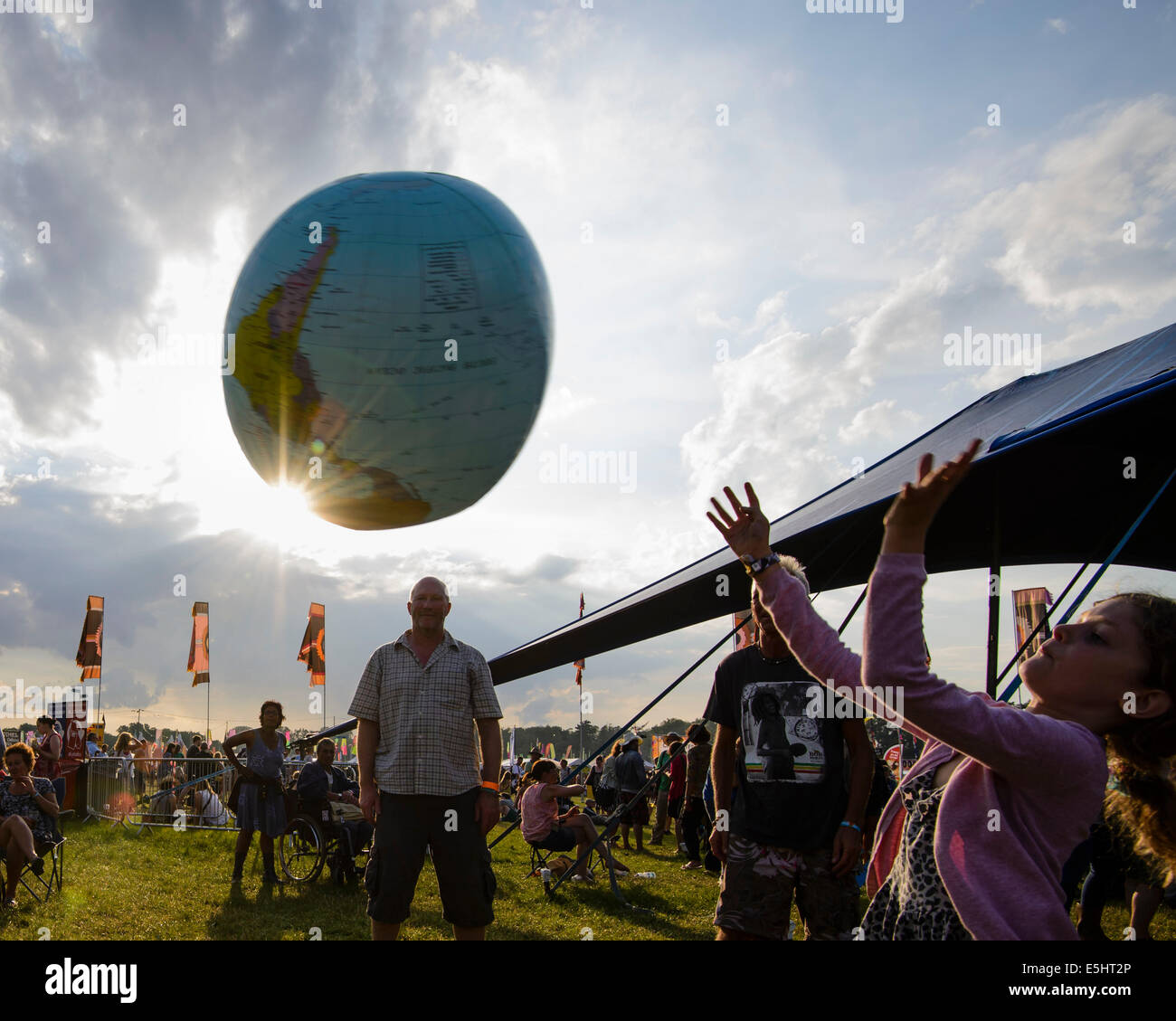 Malmesbury, UK, 25/07/2014 : Atmosphère au monde - WOMAD de la musique, des arts et de la danse. Une famille jouent avec un globe gonflable dans la lumière du soir. Photo par Julie Edwards Banque D'Images