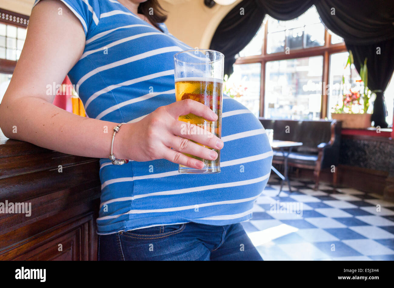Femme enceinte de boire une pinte de bière dans un pub, London, England, UK Banque D'Images