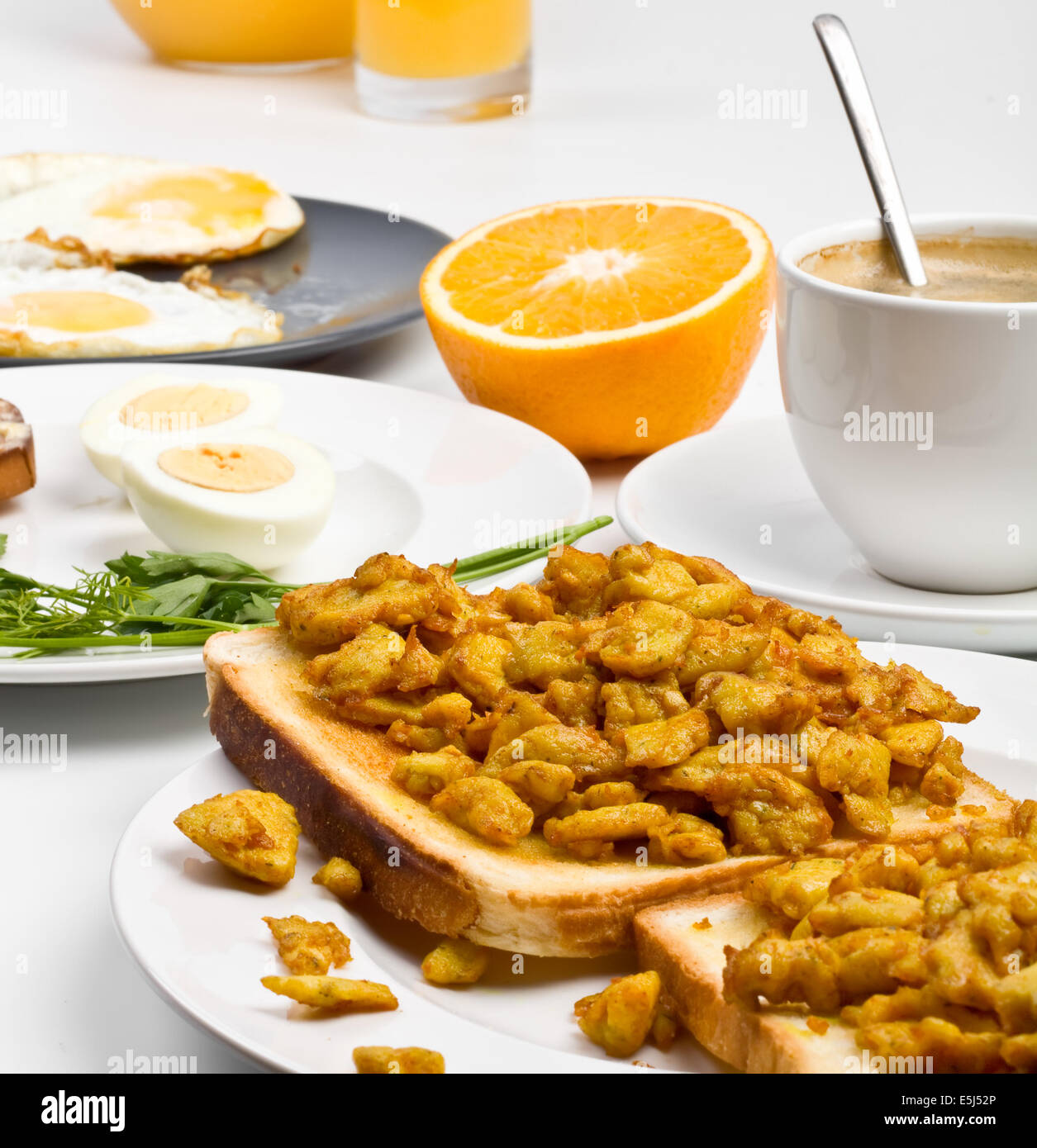 Repas Petit déjeuner - oeufs brouillés sur des toasts, œufs durs, œufs frits, la moitié d'une orange et une tasse de café Banque D'Images