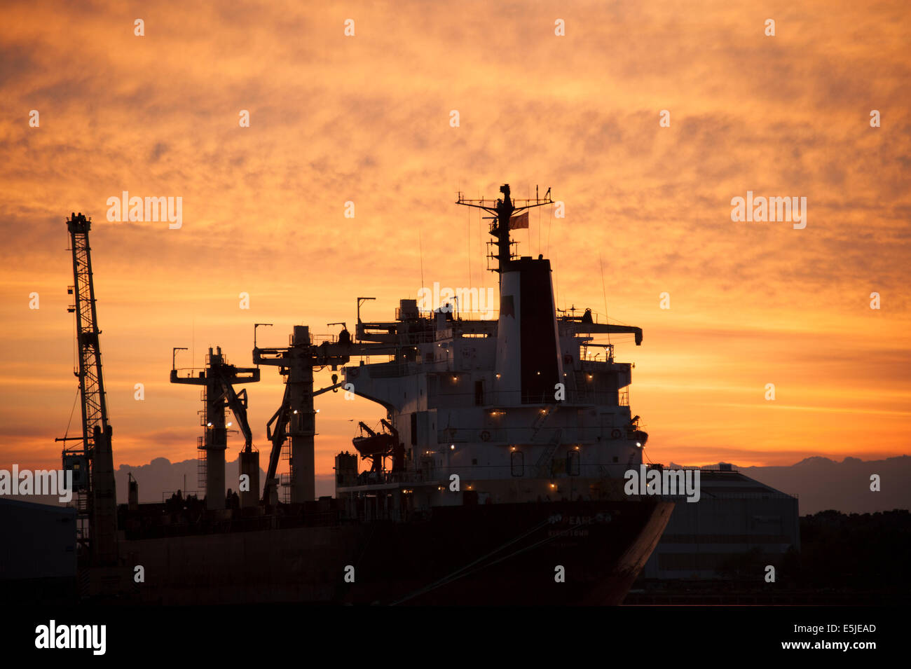 Navire à quai au coucher du soleil Ciel orange rouge silhouette Banque D'Images