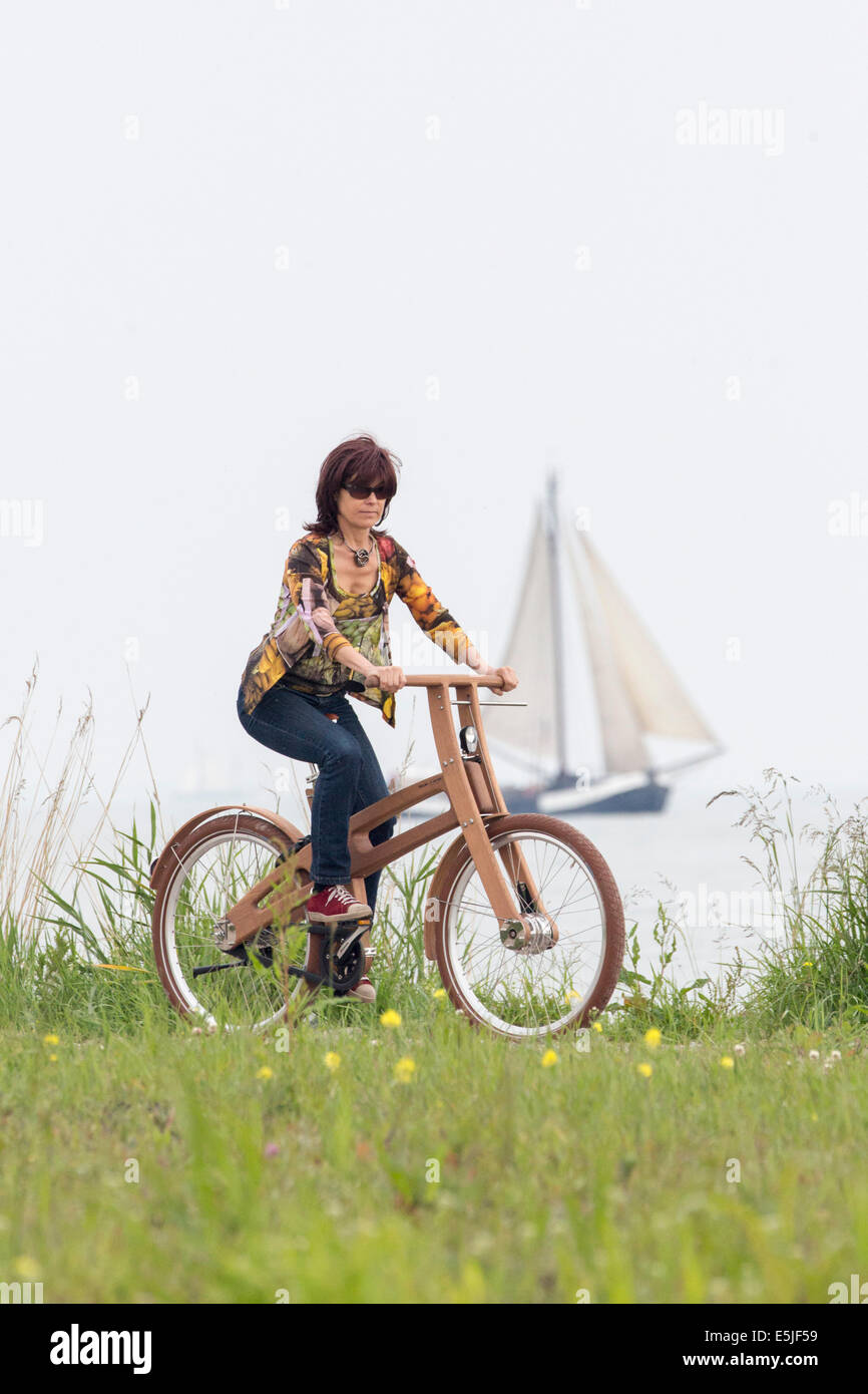 Pays-bas, Pingjum, Woman Riding the Bough Vélo. Le Dutch Design vélo en bois est une création de Jan Gunneweg. Bateau à voile Banque D'Images