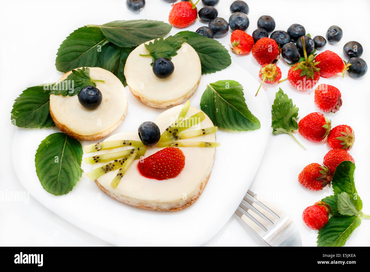 Crème glacée à la recherche animale drôle comme visage décoré par des bleuets, fraises et menthe on white plate Banque D'Images