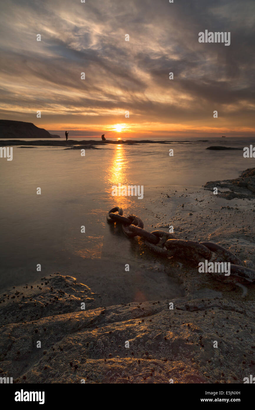 Deux jeunes hommes la pêche sur le rivage à Staithes sur la côte du Yorkshire du nord au coucher du soleil au milieu de l'été. Banque D'Images