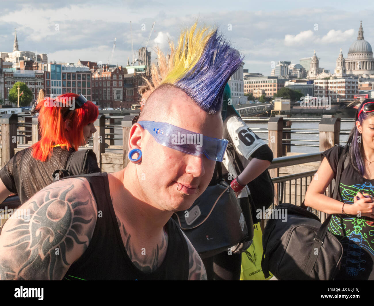 Mode de vie moderne : un jeune homme avec des tatouages, piercings lèvre et un gel de couleur punk Mohican hairstyle et lunettes cool blue, South Bank, Londres Banque D'Images