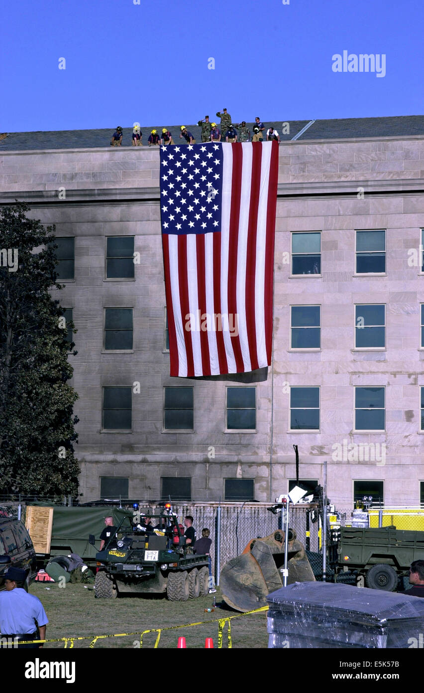 Les pompiers et les militaires se déploient le drapeau américain le long de la façade du pentagone près de l'emplacement de l'accident par suite des attaques terroristes du 12 septembre 2001 à Arlington, VA. Banque D'Images