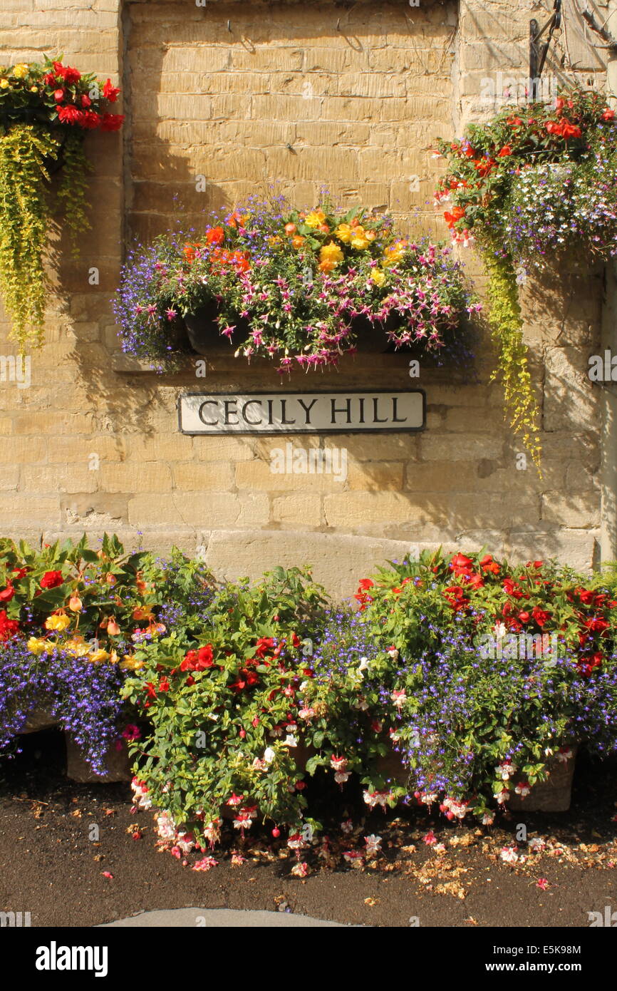 Paniers suspendus colorés et chaleureux en pierre de Cotswold couleur miel, Cecily Hill, Cirencester, Gloucestershire, England, UK Banque D'Images