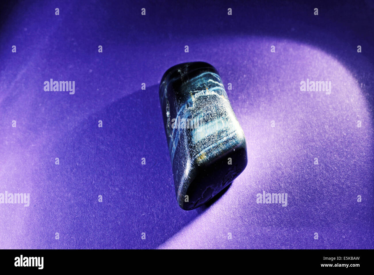 Hawk Eye gem stone macro sur un fond violet. Banque D'Images