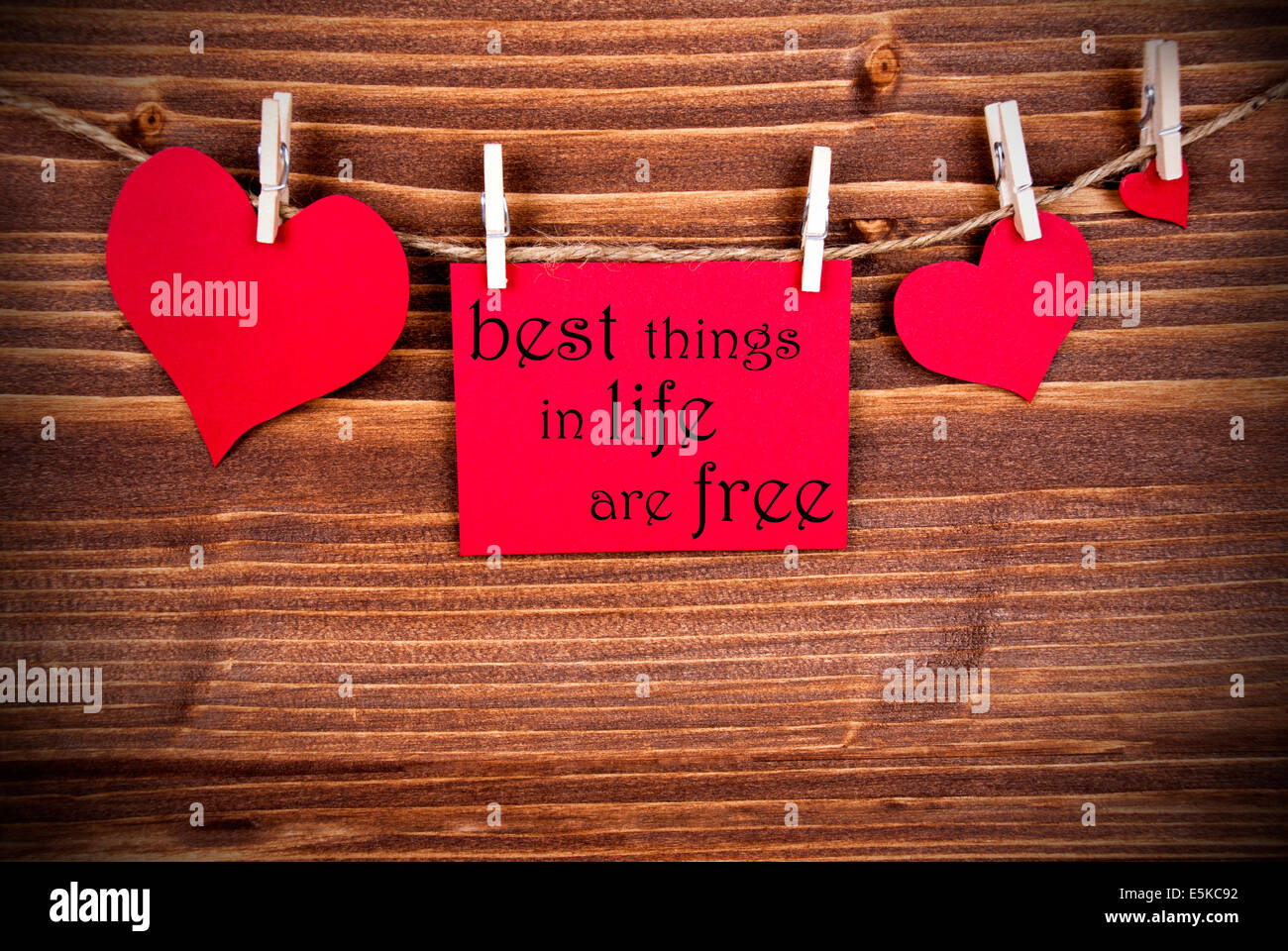Le Dit meilleures choses dans la vie sont gratuites sur une étiquette rouge avec des Cœurs sur une ligne pendaison sur fond de bois Banque D'Images