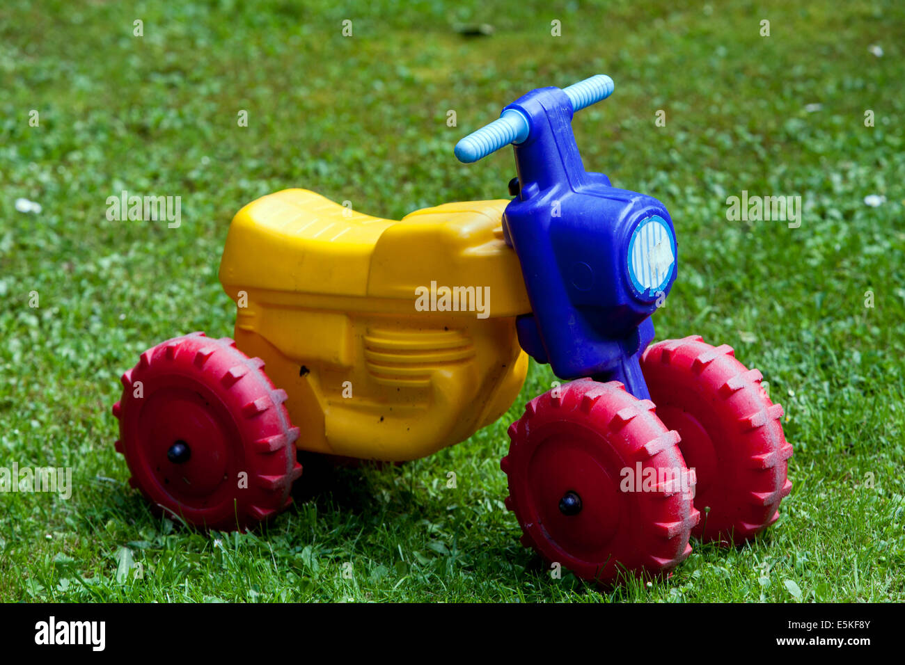 Vélo jouet coloré laissé seul dans le vélo de jardin sur la pelouse Banque D'Images