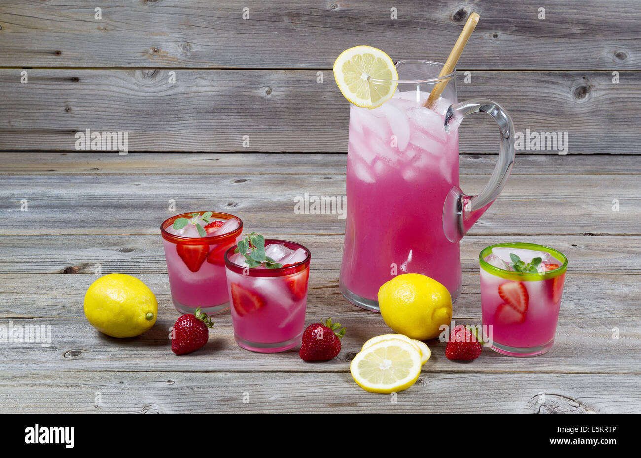 Vue de face de la limonade rose fraîchement faite avec des citrons entiers, les fraises et les verres remplis sur bois rustique Banque D'Images