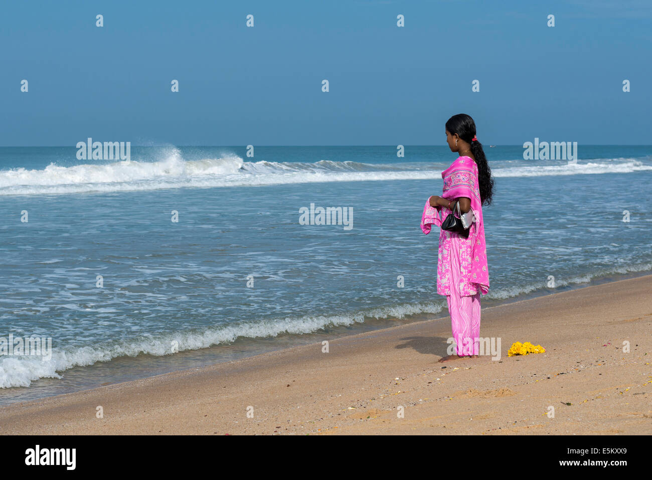 Femme portant un shalwar kameez rose debout sur la plage face à la mer, Munnar, Kerala, Inde Banque D'Images