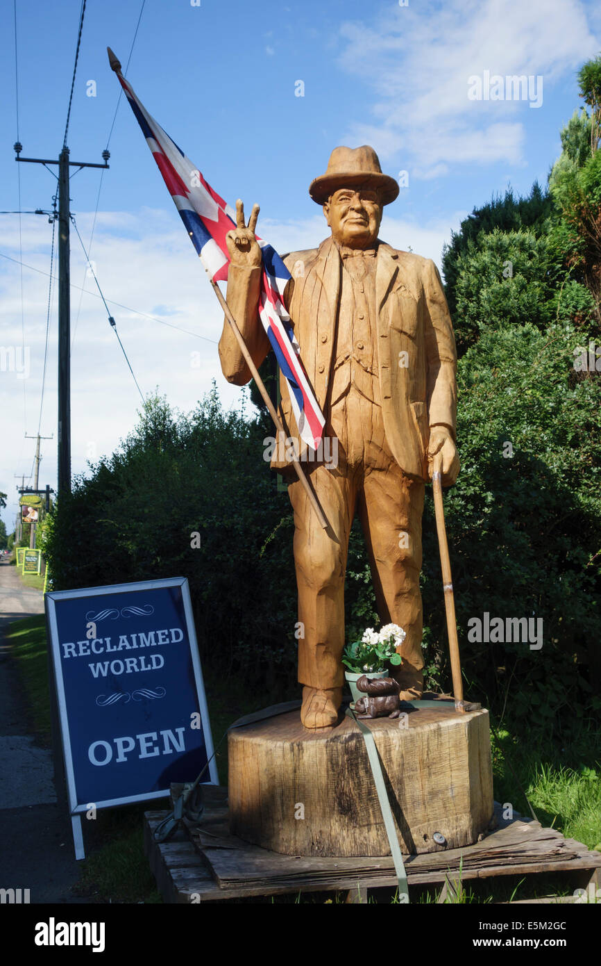 La sculpture sur bois de Winston Churchill par le bord de la route à l'extérieur d'un chantier de remise en état dans le Shropshire, Angleterre Banque D'Images