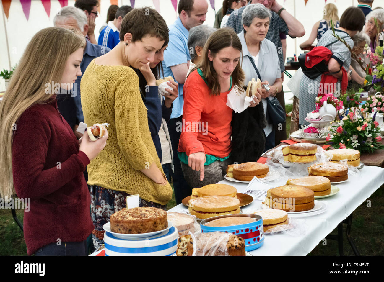 L'inspection des gâteaux faits maison à une fête du village, UK Banque D'Images