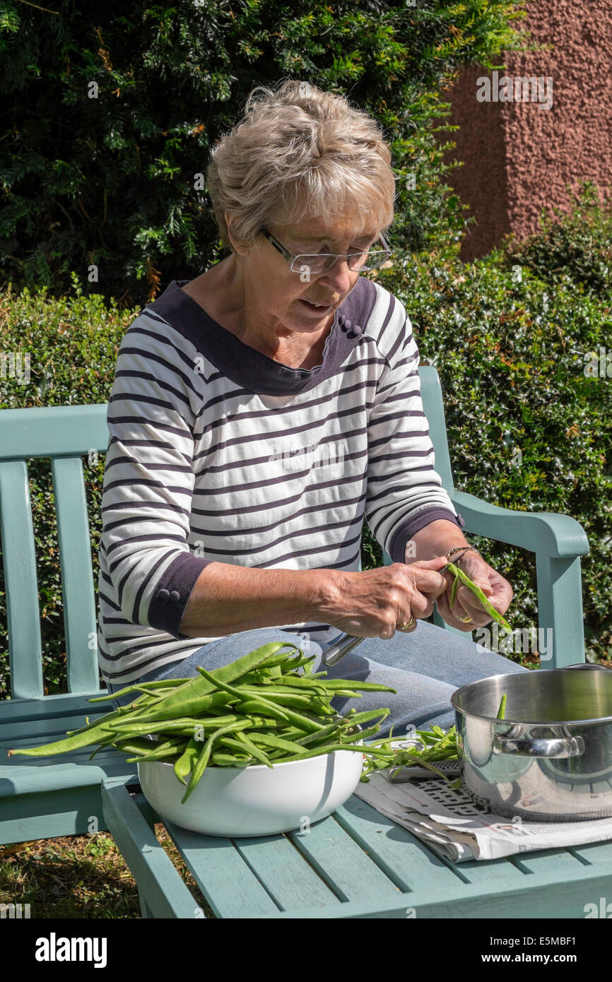 Femme plus âgée d'arthrite rhumatoïde en jardin UK slicing issus de chez green/haricots prête pour le gel pour une utilisation ultérieure Banque D'Images