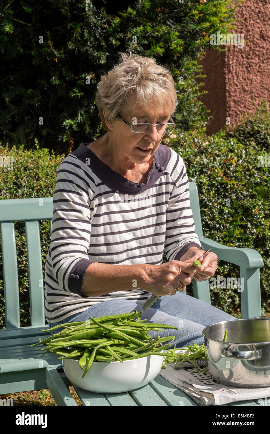 Femme plus âgée d'arthrite rhumatoïde en jardin UK slicing issus de chez green/haricots prête pour le gel pour une utilisation ultérieure Banque D'Images