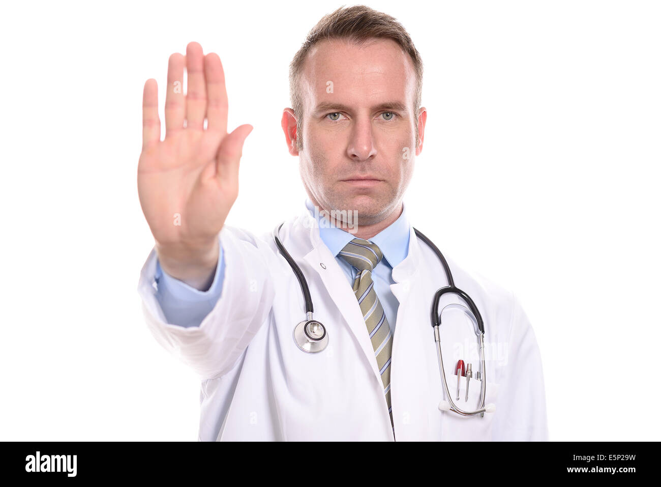 Médecin ou infirmier portant un manteau de laboratoire levant la main dans un geste d'arrêt avec une expression implacable stern Banque D'Images