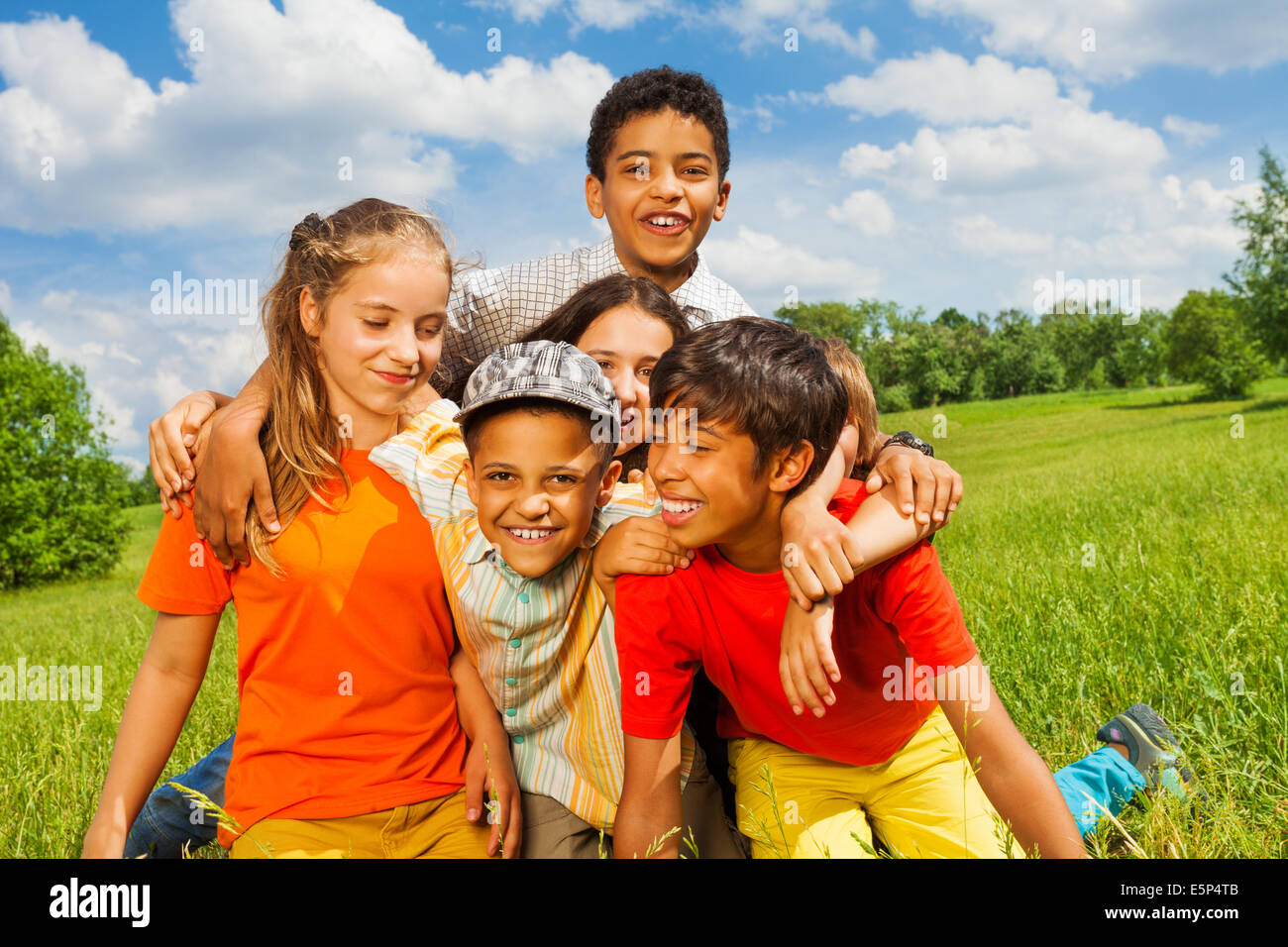 Cinq enfants heureux ensemble en dehors de câlins Banque D'Images