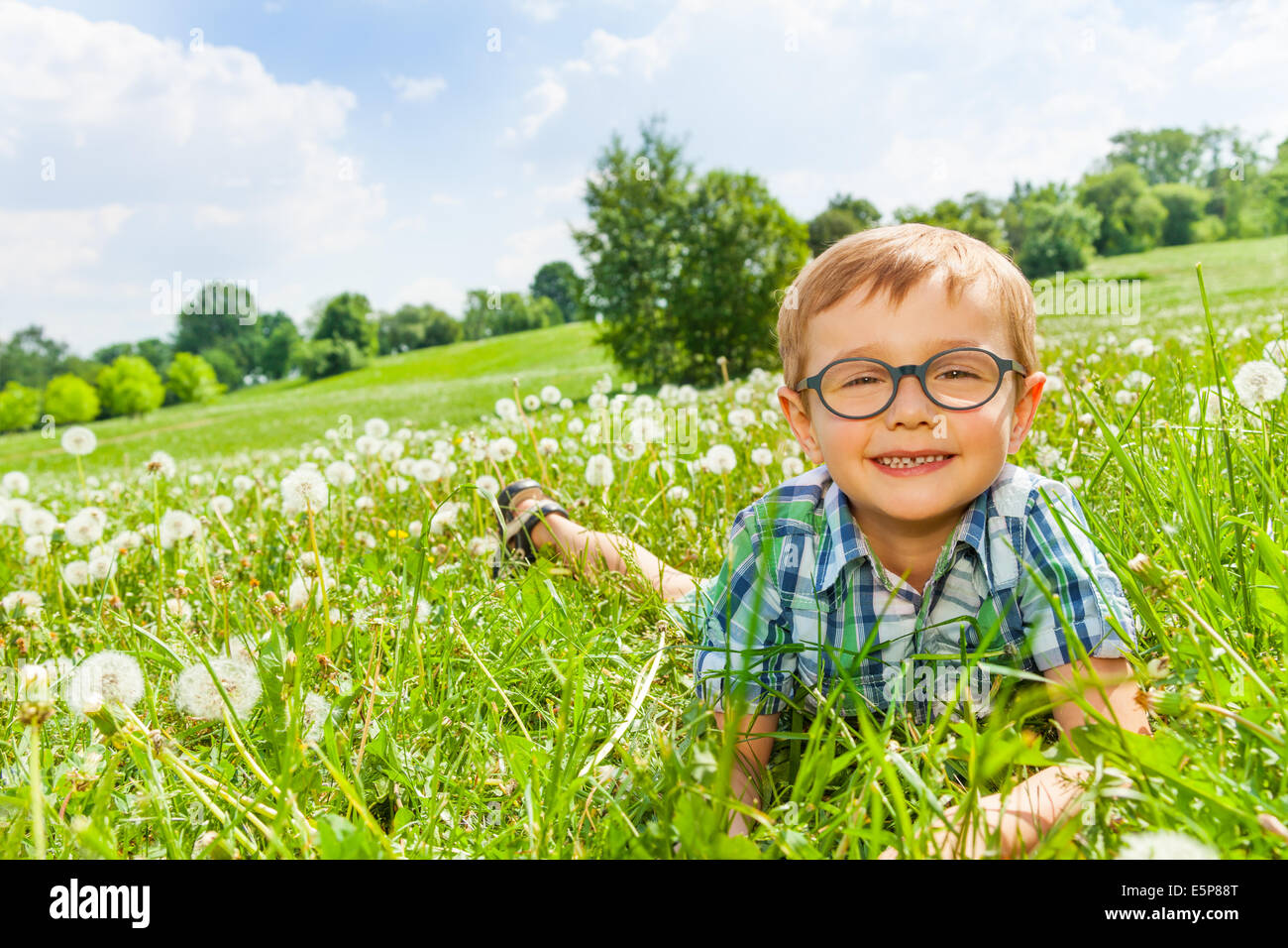 Petit garçon sourit portant sur une herbe Banque D'Images
