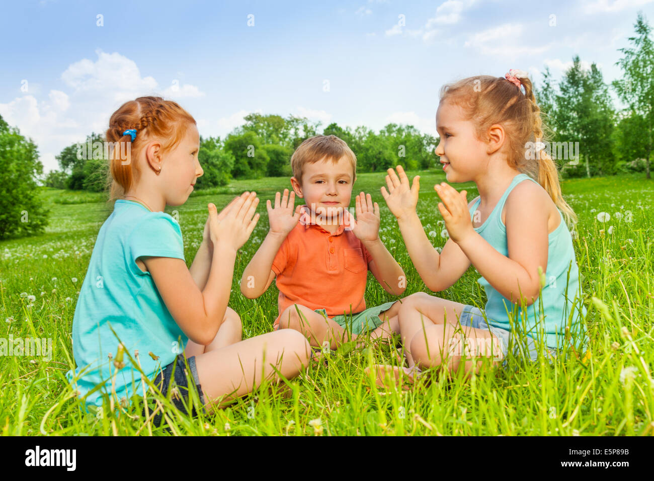 Trois enfants jouant sur une herbe Banque D'Images