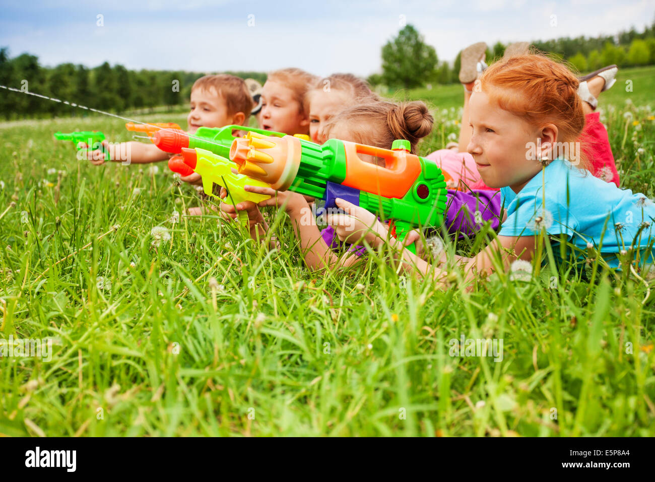 Cinq enfants jouent avec des pistolets à eau Banque D'Images
