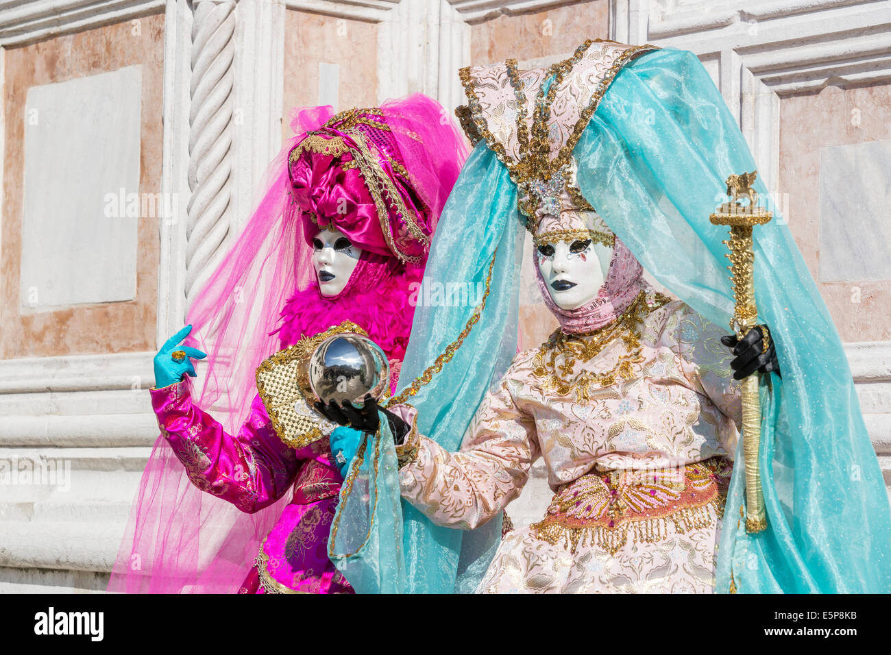 Paire de femmes dans l'élaboration de costumes de carnaval et de lavande crème avec boule à surface réfléchissante à l'extérieur de l'église San Zaccaria à Venise. Banque D'Images