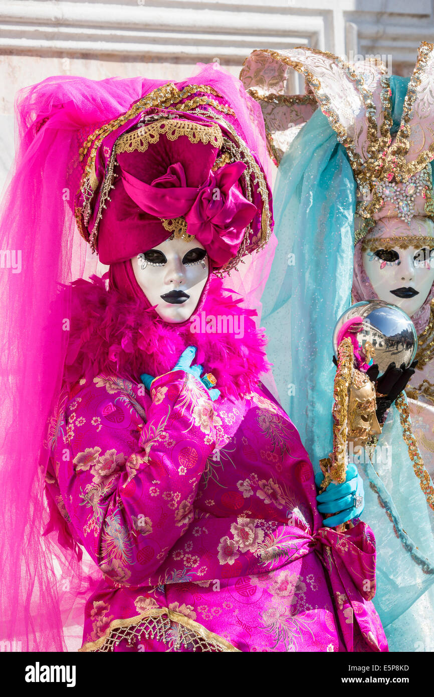 Paire de femmes dans l'élaboration de costumes de carnaval et de lavande crème avec boule à surface réfléchissante à l'extérieur de l'église San Zaccaria à Venise. Banque D'Images