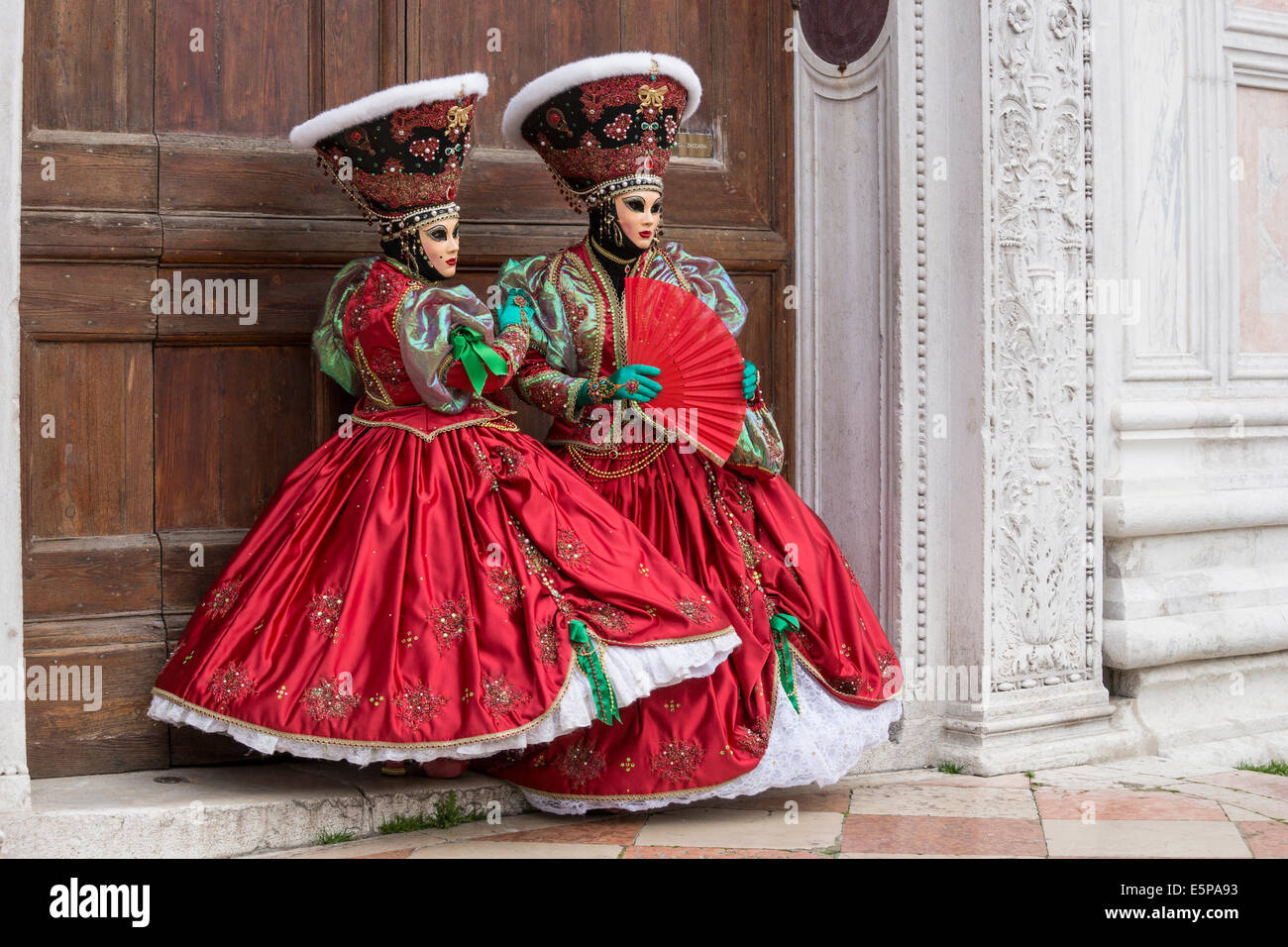 Paire de femmes dans l'élaboration de costumes stylisés vert rouge avec en face de la porte de l'église San Zaccaria pendant le carnaval de Venise Banque D'Images