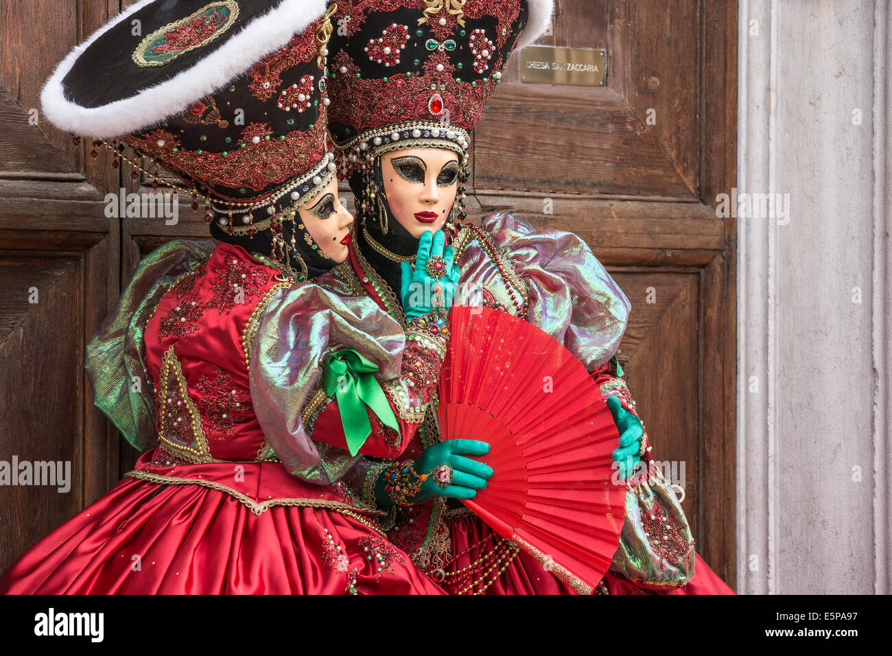 Paire de femmes dans l'élaboration de costumes stylisés vert rouge avec en face de la porte de l'église San Zaccaria pendant le carnaval de Venise Banque D'Images