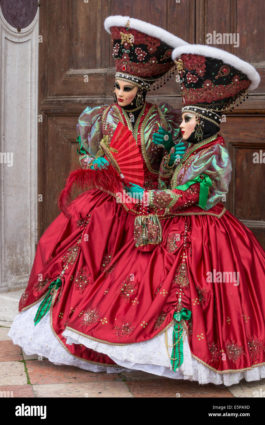 Paire de femmes dans l'élaboration de costumes stylisés vert rouge avec en face de la porte de l'église San Zaccaria pendant le carnaval de Venise Banque D'Images