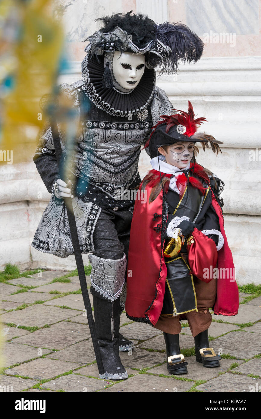 L'homme à élaborer en noir & argent avec cavalier habillé en garçon cat face paint à l'église San Zaccaria, Carnaval de Venise. Banque D'Images