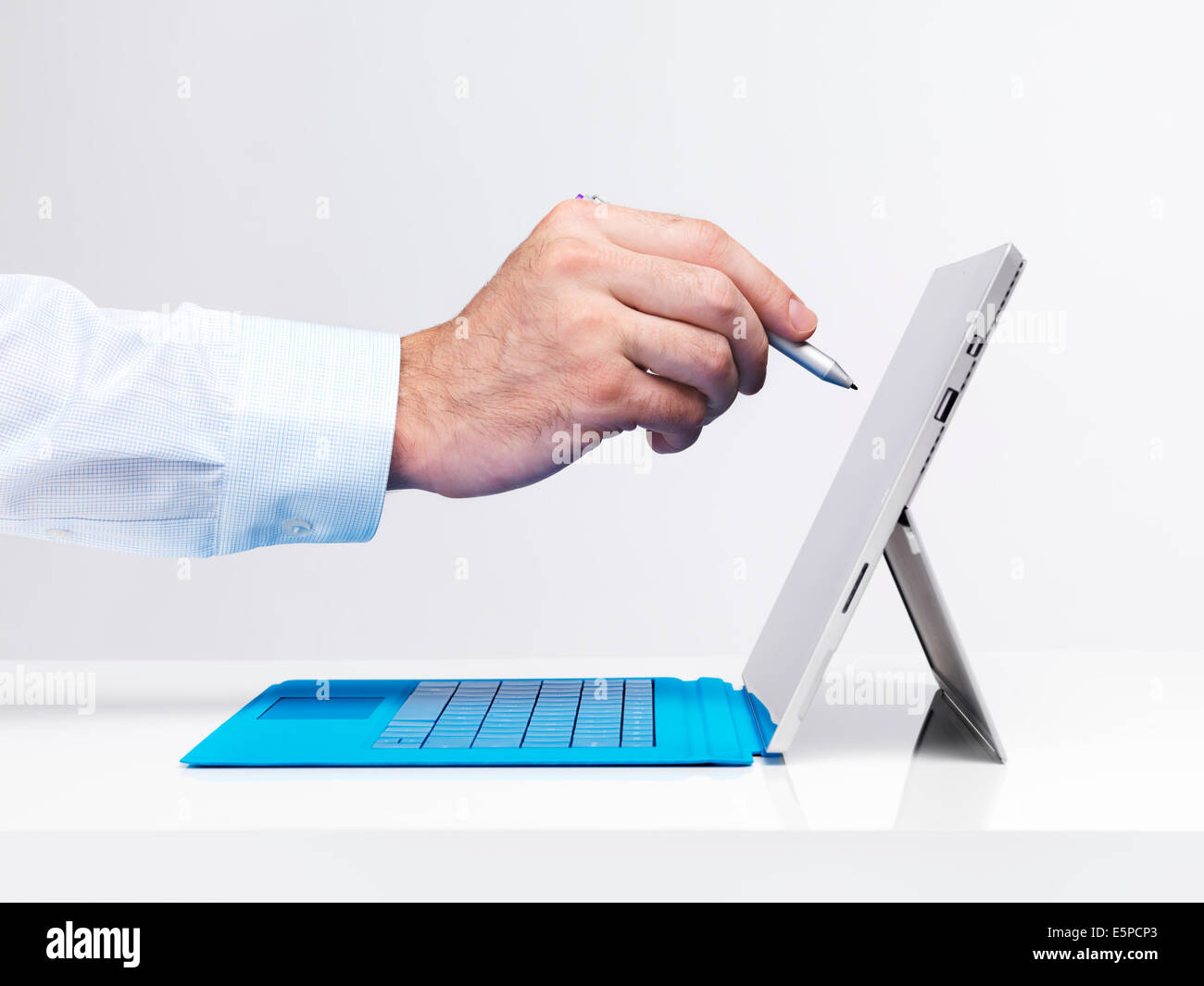 Libre de la main d'un homme avec un stylo de toucher de l'écran Microsoft Surface Pro 3 tablet ordinateur isolé sur fond blanc Banque D'Images