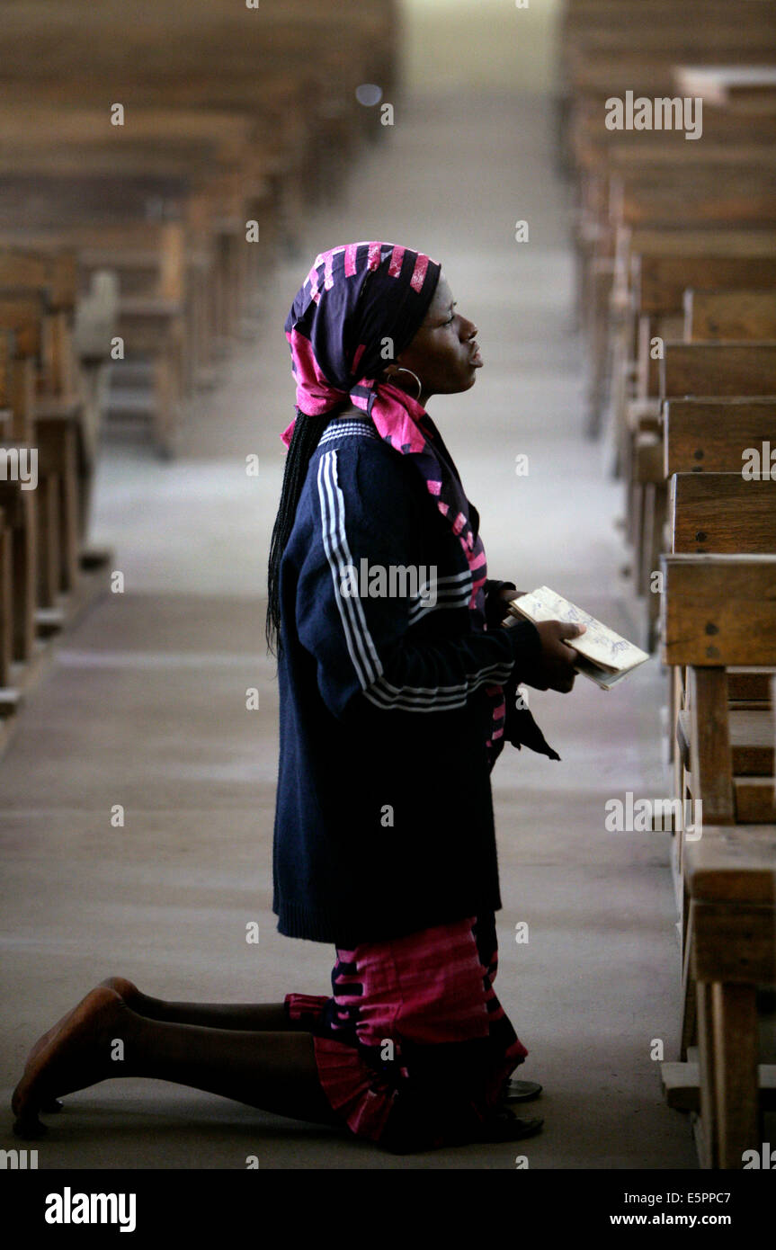 Femme en prière à genoux dans une église catholique à Maiduguri, Nigéria Banque D'Images
