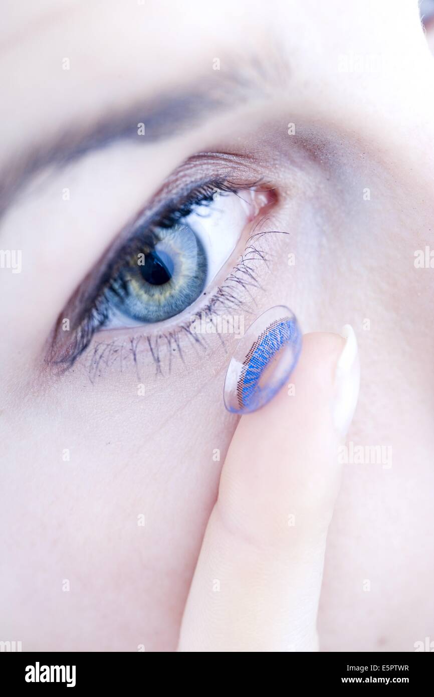 Mettre une femme de lentilles de contact de couleur dans l'œil. Banque D'Images