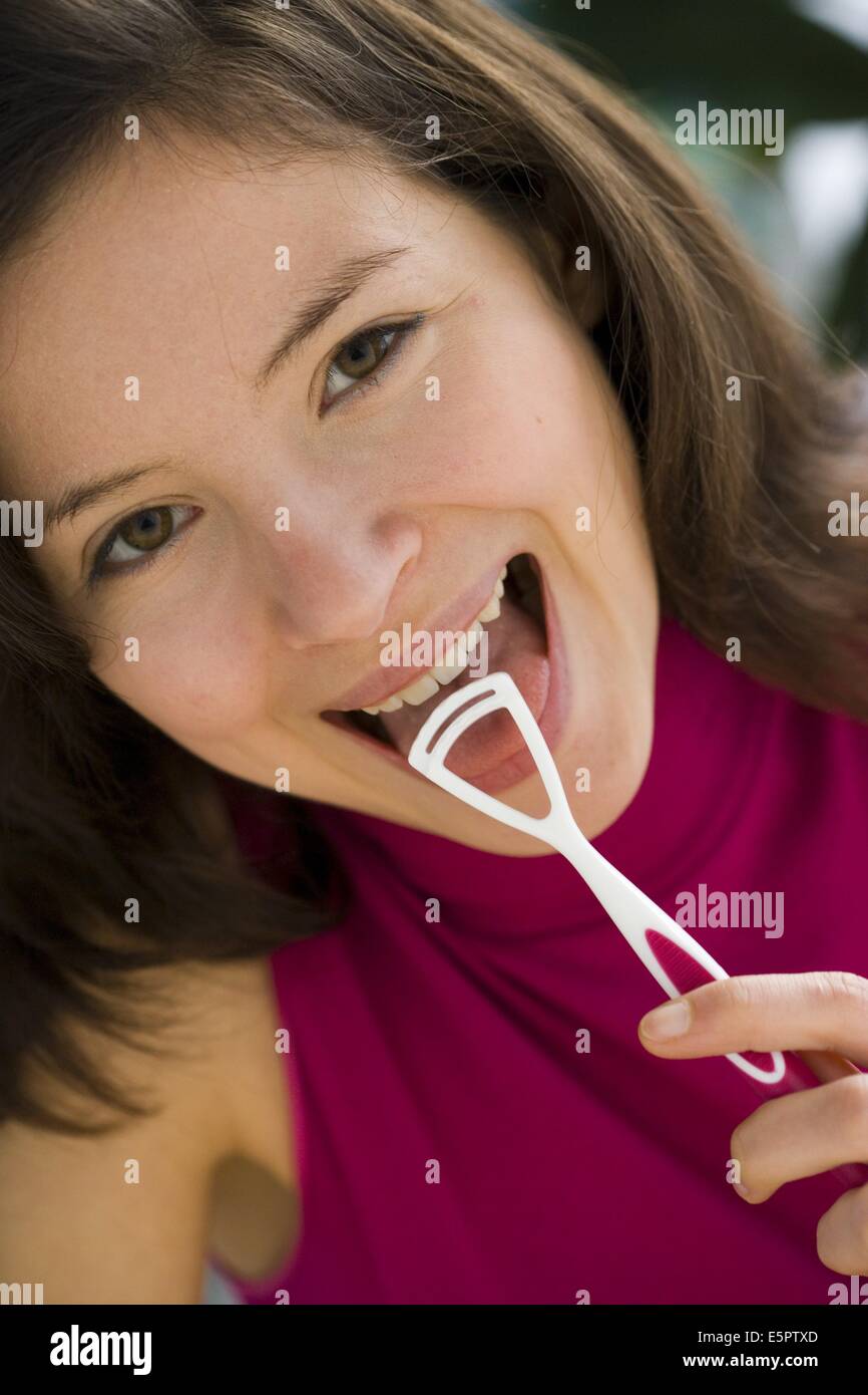 Woman brushing sa langue avec une brosse-langue pour éliminer les bactéries responsables de la mauvaise haleine. Banque D'Images