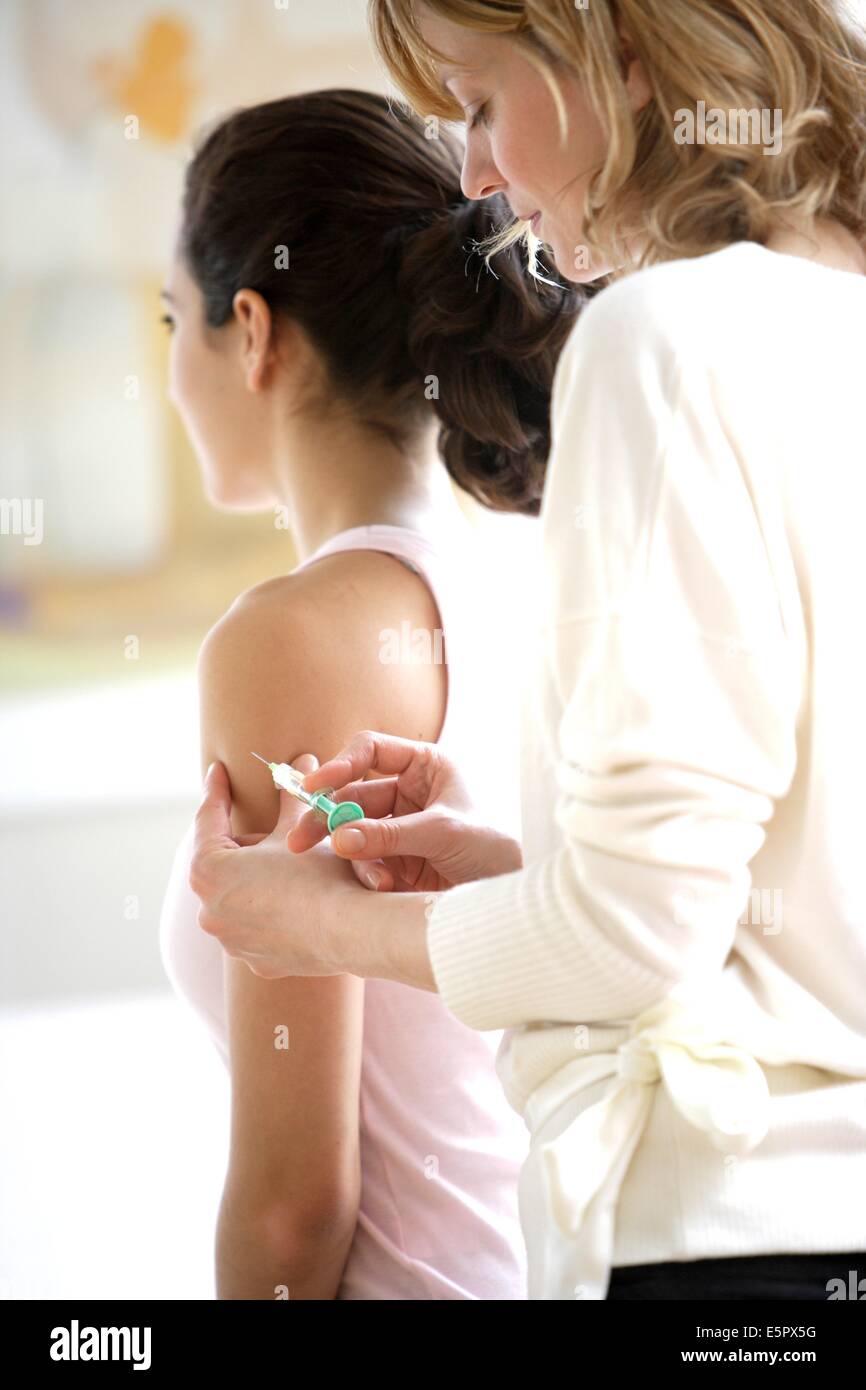 Femme qui reçoit la vaccination (vaccin Gardasil) contre différents types de papillomavirus humains (HPV) responsable de Banque D'Images