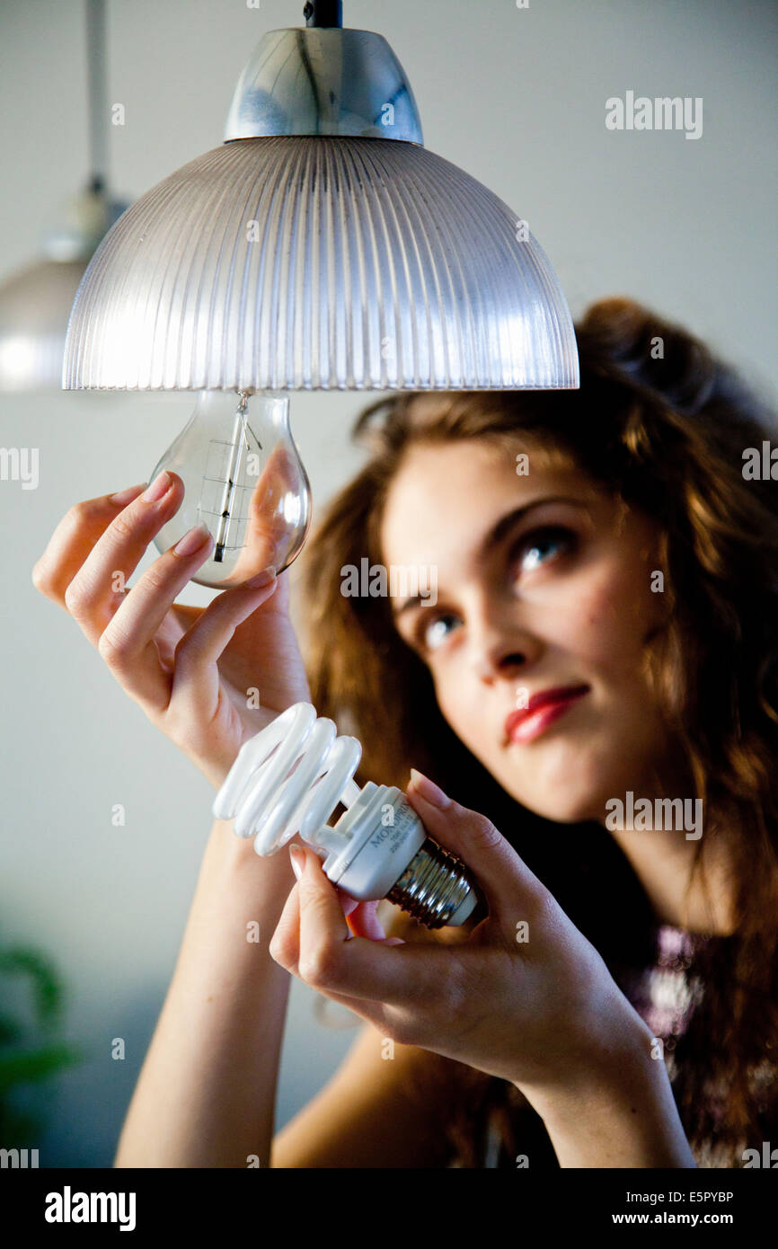 Femme mettant un energy saving lightbulb. Banque D'Images