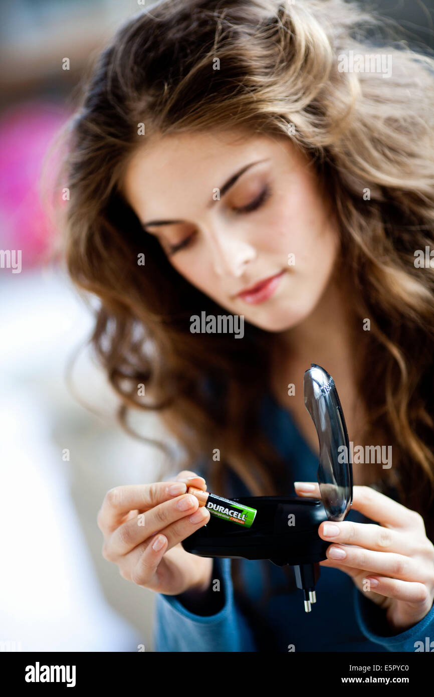 Femme à l'aide du chargeur pour batteries rechargeables. Banque D'Images