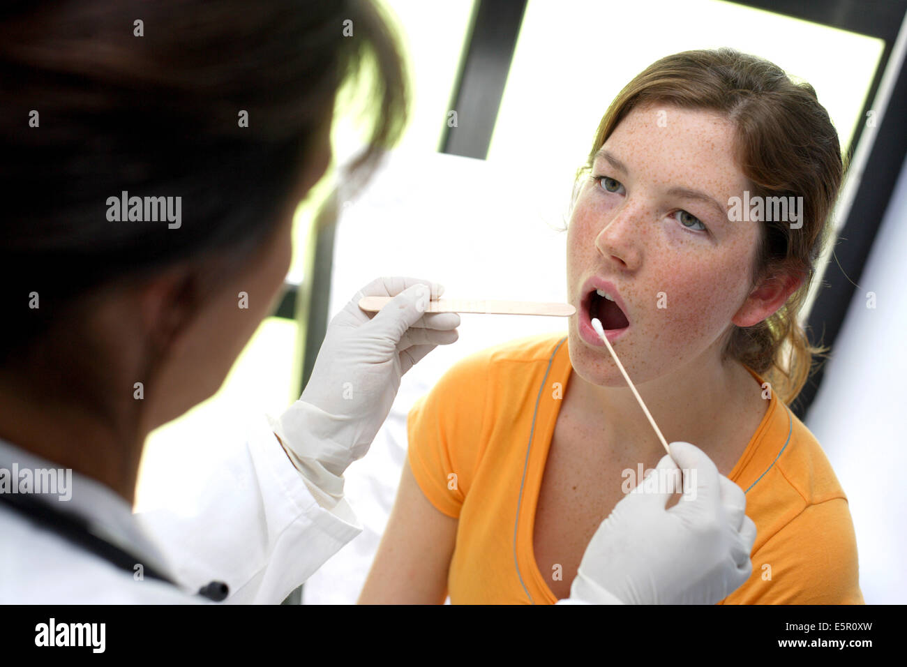 Médecin à l'aide d'un coton-tige pour prélever un échantillon de sa gorge du patient. Banque D'Images