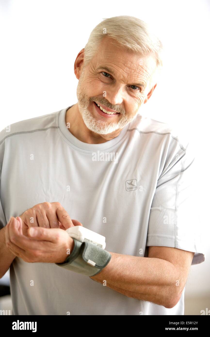 L'homme de prendre sa pression artérielle avec un tensiomètre. Banque D'Images