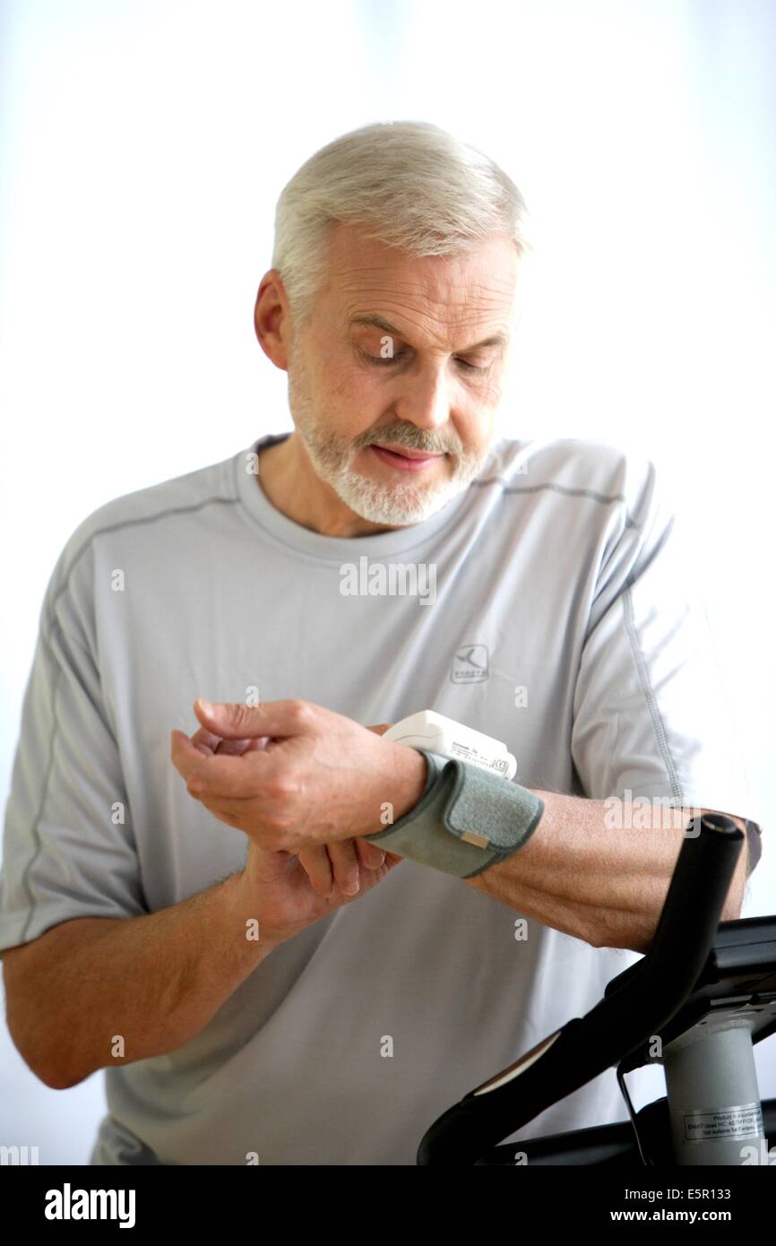 L'homme de prendre sa tension artérielle avec un appareil portable de mesure de tension artérielle après l'activité physique. Banque D'Images