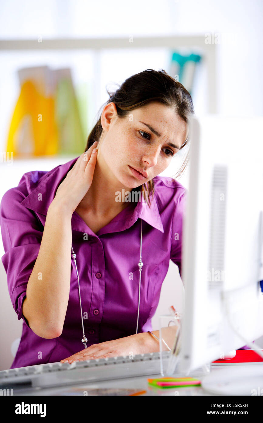 Femme souffrant de douleur au cou dans le bureau. Banque D'Images