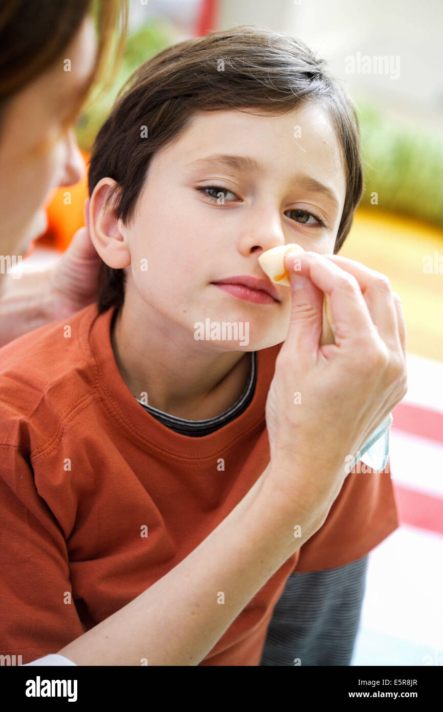 Enfant de 8 ans avec un saignement de nez. Banque D'Images
