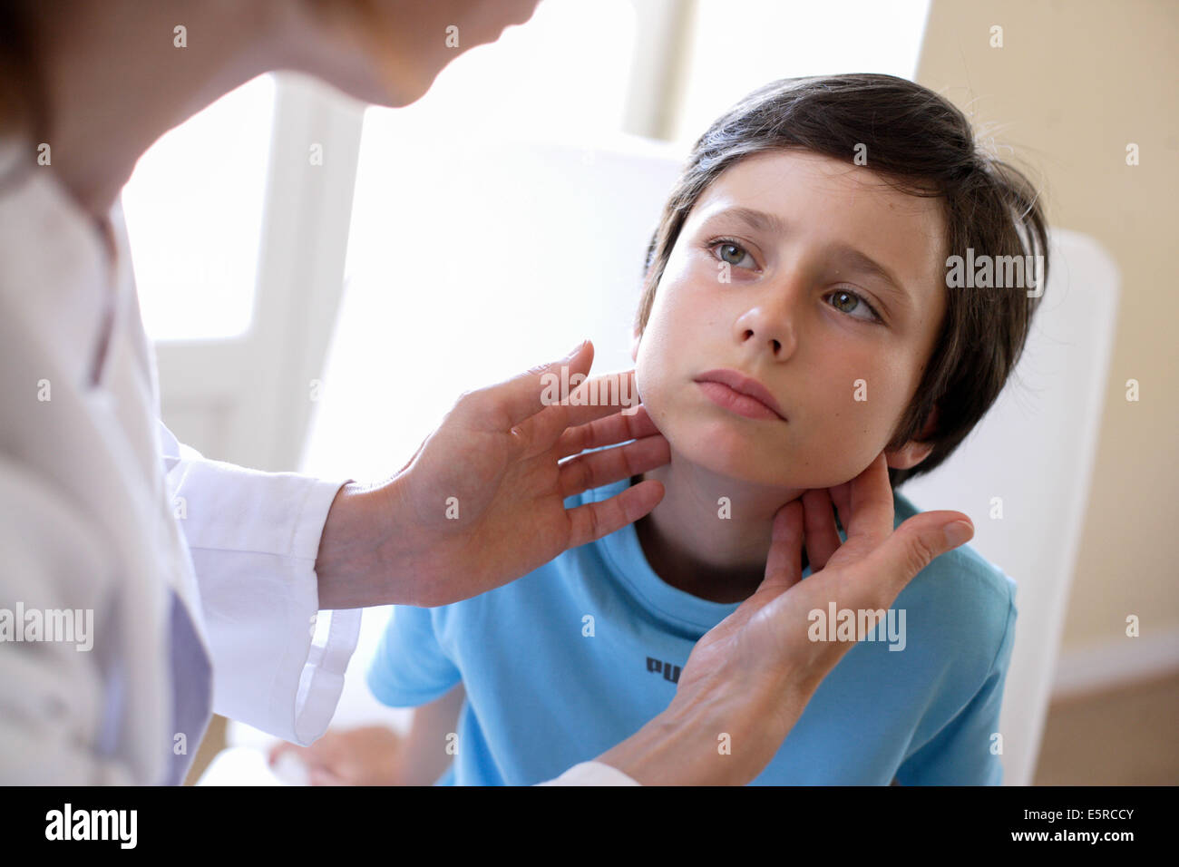 Médecin d'examiner les ganglions lymphatiques d'un garçon de 9 ans. Banque D'Images