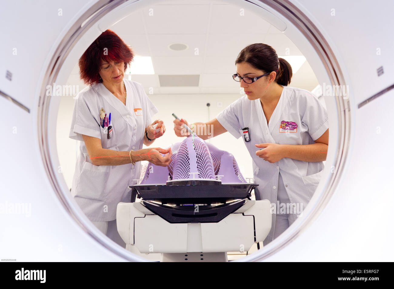 Les radiographes radiothérapie du cancer du cerveau mâle la préparation d'un patient pour une tomodensitométrie (TDM), à l'étape préparatoire Banque D'Images