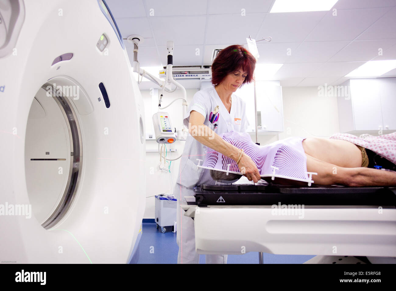 Radiographerpreparing la radiothérapie du cancer du cerveau d'un homme patient pour une tomodensitométrie (TDM), à l'étape préparatoire Banque D'Images