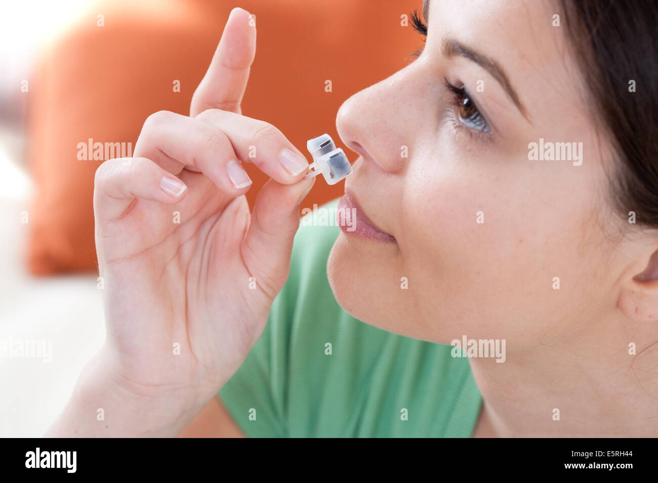 Femme à l'aide d'un filtre nasal Nosecaps® contre les allergies, la pollution ou le ronflement. Banque D'Images